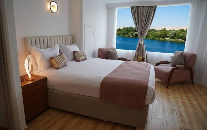 Bright, modern river-view bedroom with large window framing the Nile and desert hills beyond
