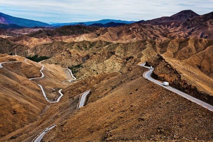 Serpentine mountain road weaves through barren brown ridges of the High Atlas.