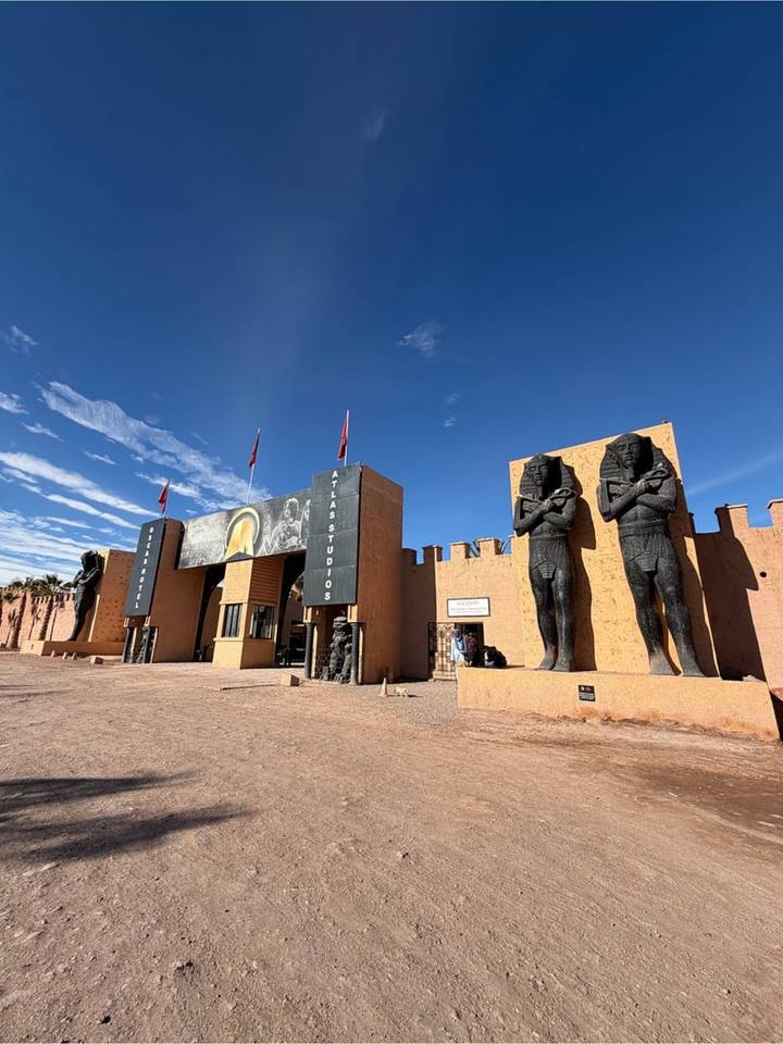 Fort-like entrance of Atlas Studios flanked by large pharaonic statues under clear skies.