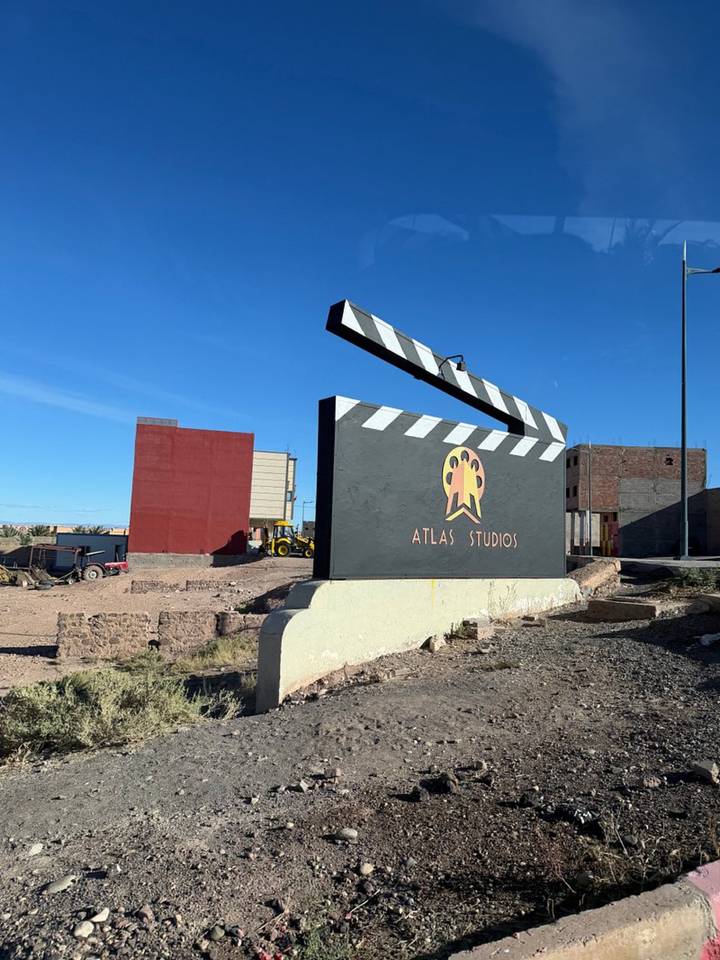 Cinematic clapperboard monument reading Atlas Studios stands in the Moroccan desert.