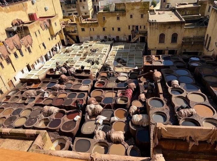 Overhead view of the Chouara leather tannery with workers tending circular dye vats in Fes
