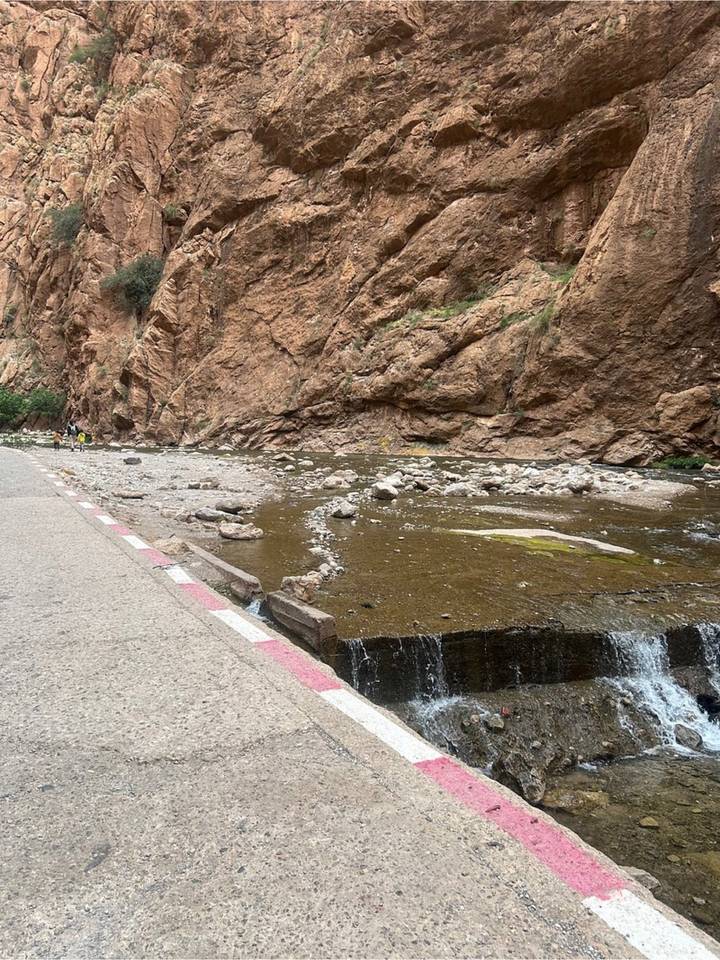 Narrow rocky gorge with a shallow stream flowing beside a roadside path
