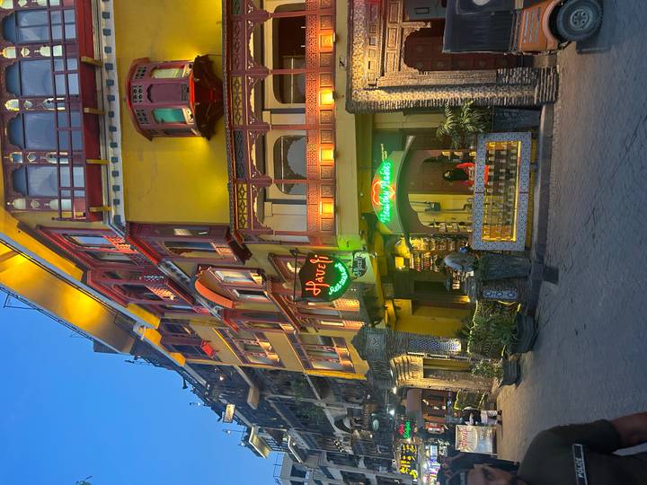 Vibrant yellow heritage building lit up at dusk with neon Haveli Restaurant sign on Lahore’s lively food street.