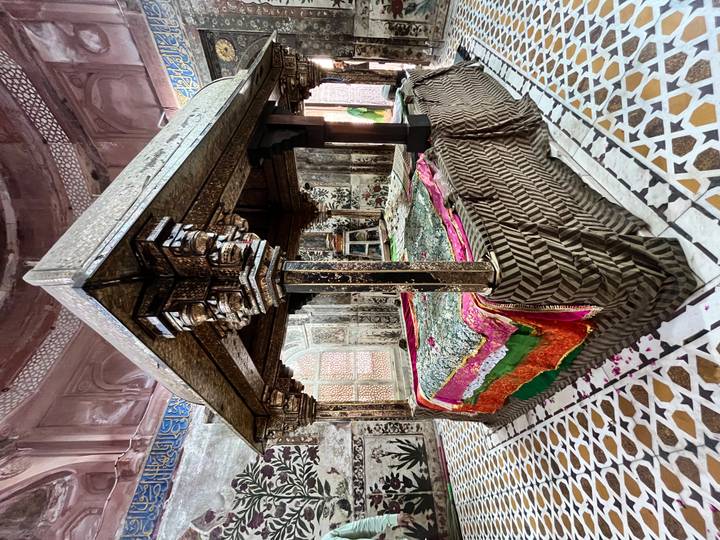 Ornate interior tomb covered with rich patterned cloth and marble tiles.