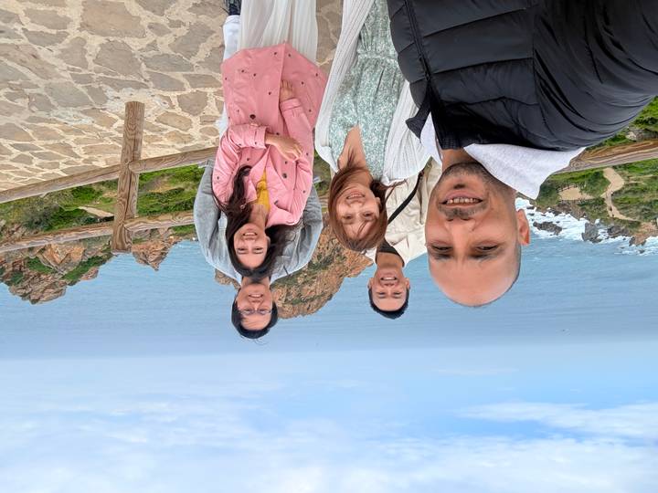 Smiling group selfie at a coastal cliff viewpoint with the ocean stretching behind them