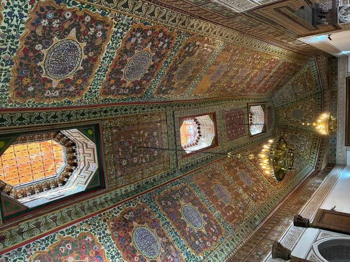 Intricately painted and carved wooden ceiling with ornate chandeliers in a Moroccan palace