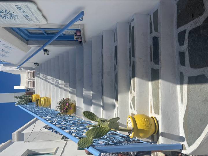 White marble staircase with blue railings and bright yellow planters leading up toward a deep blue sky.