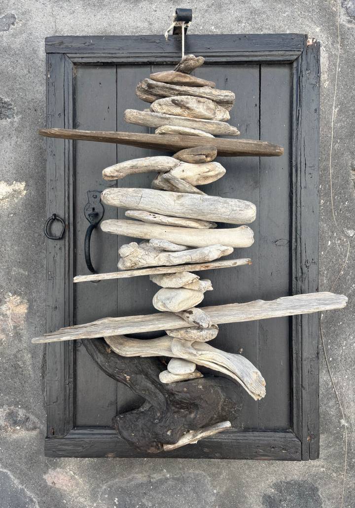 Artistic arrangement of weathered driftwood pieces mounted on a dark wooden background.