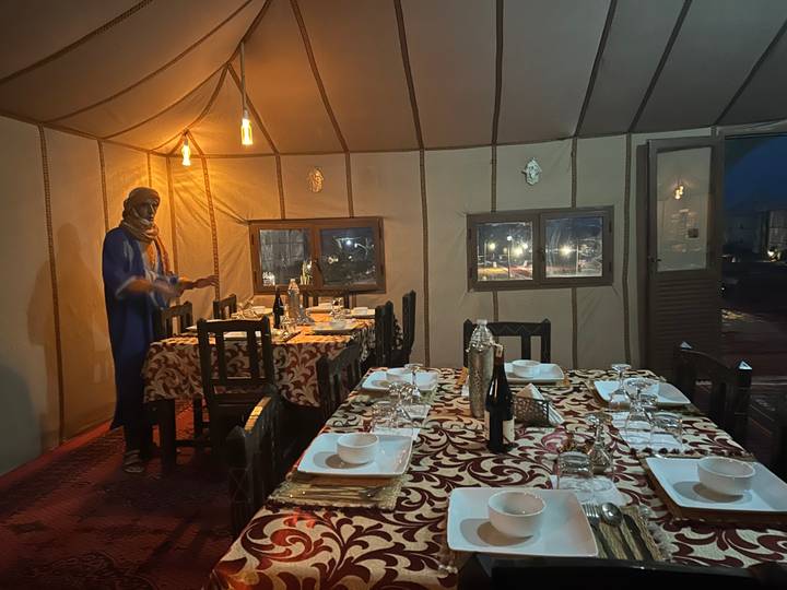 Dinner tent in the desert set with patterned tablecloths and warm lantern light.