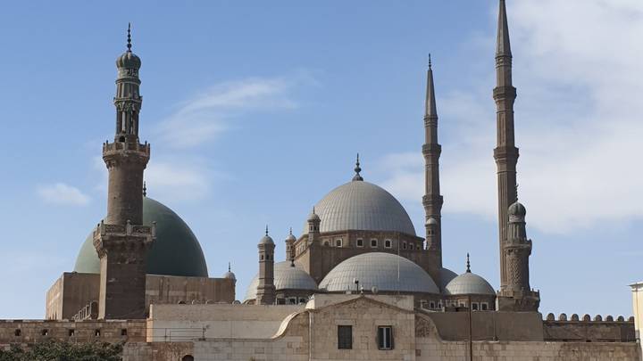The grand Mohamed Ali Mosque rises with multiple domes and slender minarets against a blue sky.