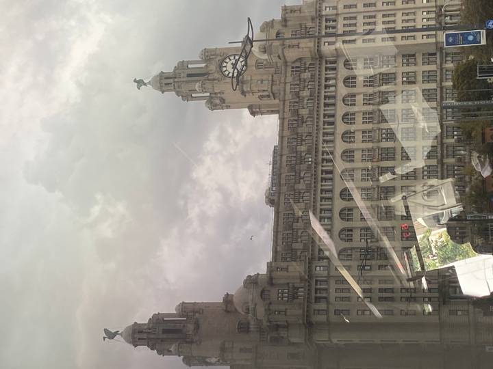 Royal Liver Building with clock tower seen through bus window reflections on a cloudy day.