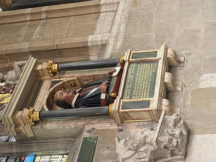 Bust monument of William Shakespeare inside a stone church alcove.