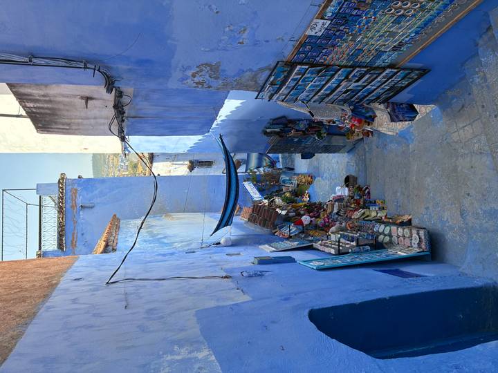 Narrow stairway market in Chefchaouen painted vivid blue, lined with colorful crafts and textiles.