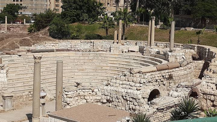 Stone Roman-era amphitheatre ruins with broken columns under bright sun.