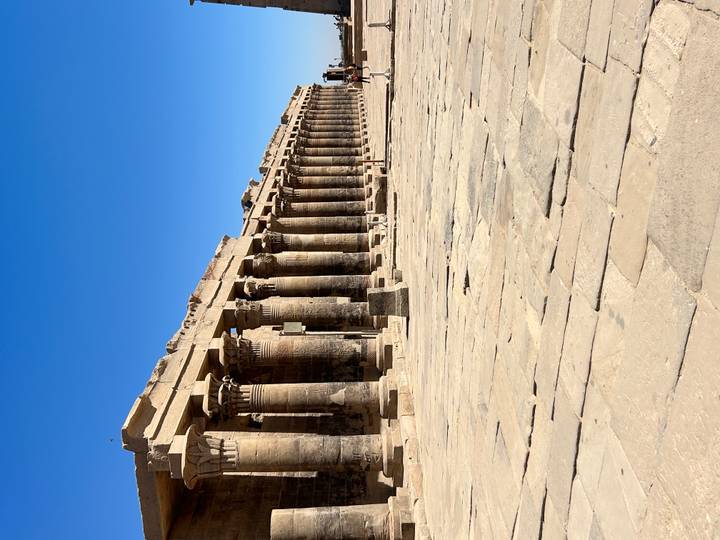 Long colonnade of Kom Ombo Temple with tall stone columns under bright sunlight.