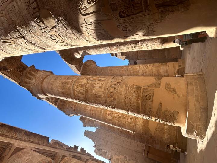 Soaring decorated columns of Karnak Hypostyle Hall casting strong shadows in afternoon light.