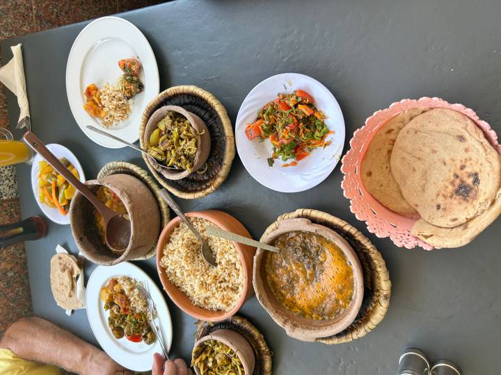 Traditional Egyptian meal laid out on a table with bowls of stews, rice, bread and pickled vegetables