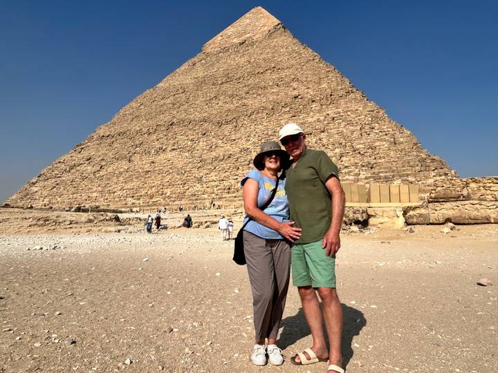 Smiling couple posing in front of the Great Pyramid on a bright day