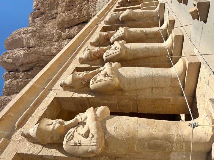 Row of colossal Osiride statues of Hatshepsut lining the terrace at Deir el-Bahri temple complex