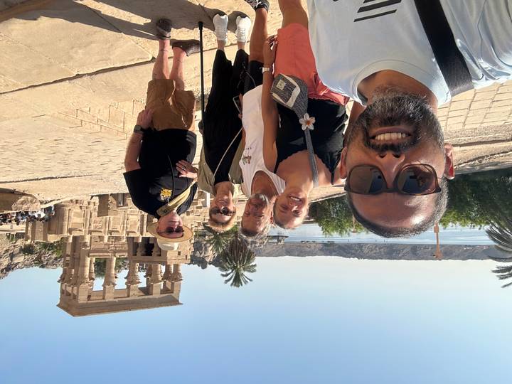 A group of travelers smiles for a selfie in front of Philae Temple beside the Nile.