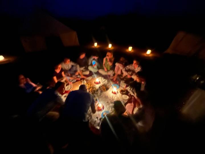 Blurry image of a group dining by candlelight at a desert camp.