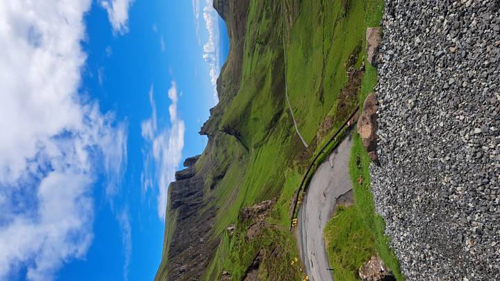 Dramatic viewpoint over the green cliffs and winding single-track road of the Quiraing, Isle of Skye.