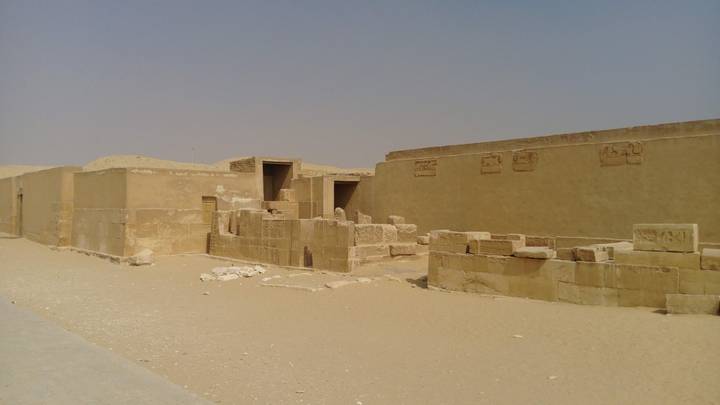 Ancient sandstone ruins in a desert landscape under a hazy sky