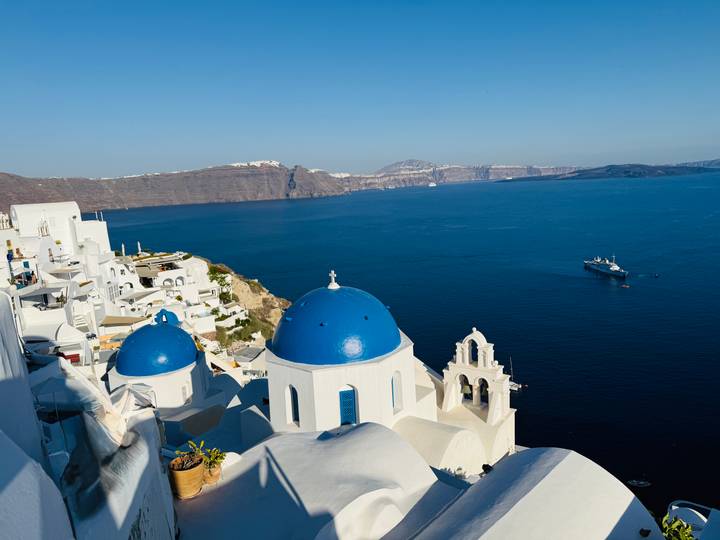 Iconic white churches with blue domes overlooking the deep blue Aegean Sea in Oia