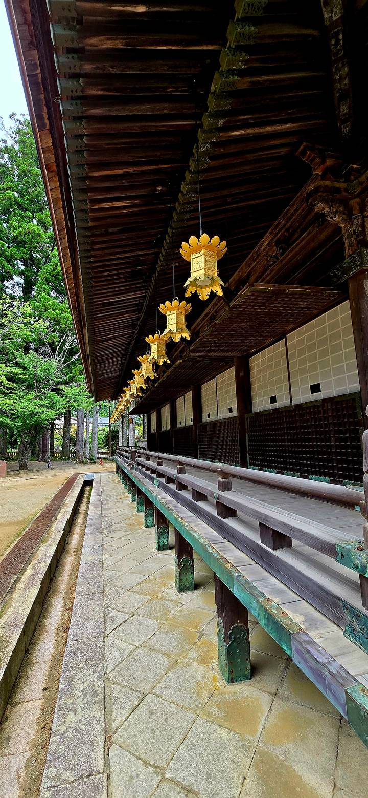 Timber temple corridor with golden lanterns hanging above polished railings