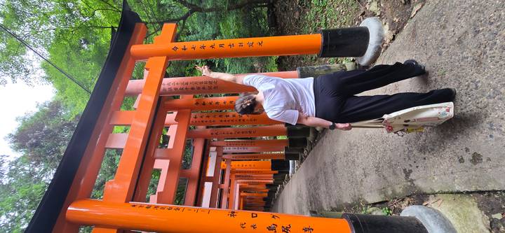 Traveler pointing upward while walking through vivid orange torii tunnel in a forest setting