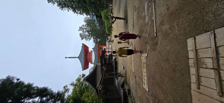 Two travelers walking toward a towering orange pagoda within a temple complex