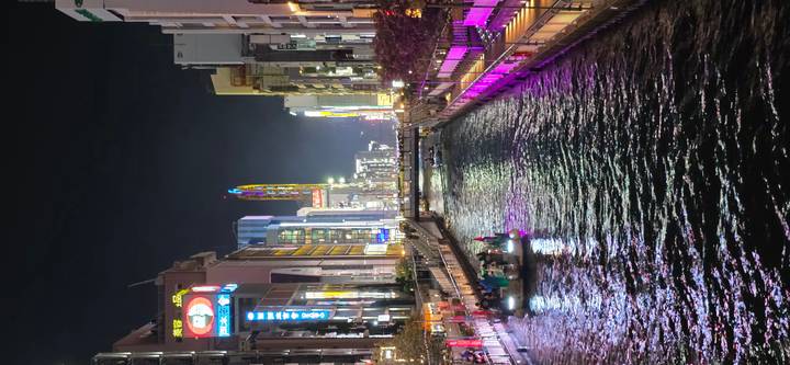 Vibrant night view of canal lined with neon signs and boat of passengers in Osaka’s Dotonbori