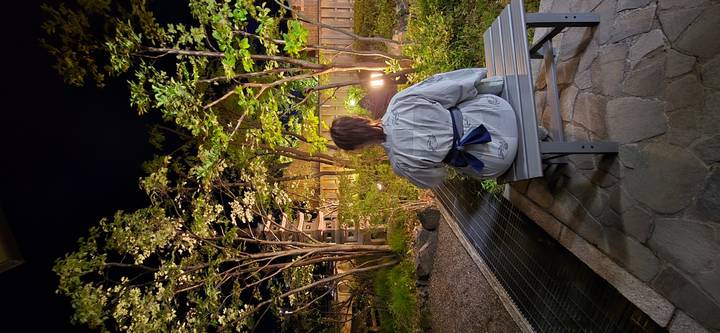 Person in yukata sits on bench enjoying a softly lit garden at night