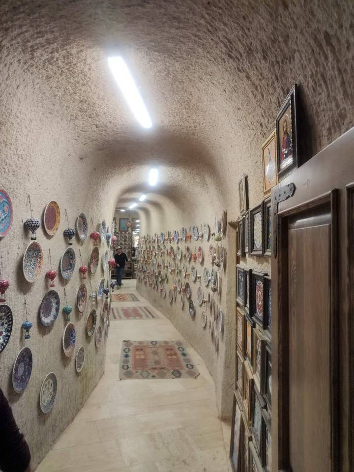Narrow arched corridor lined with colorful ceramic plates in a cave shop