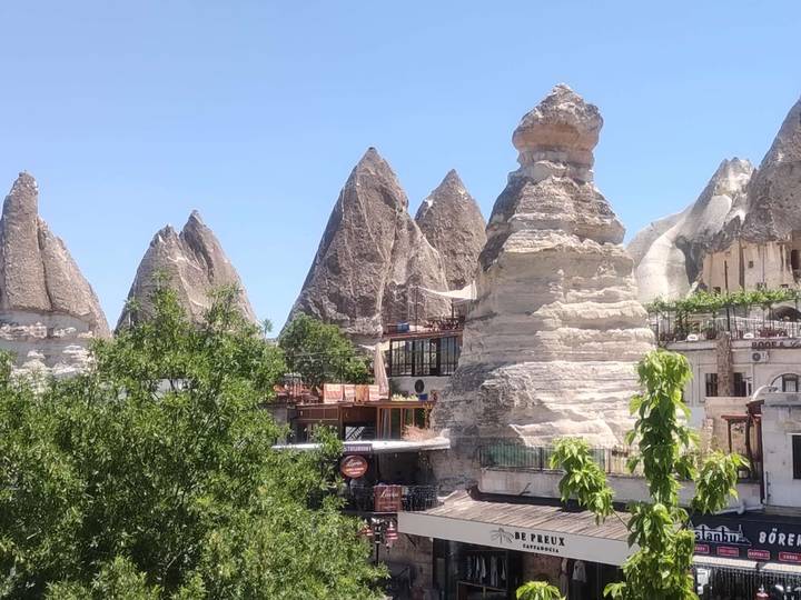 Cluster of fairy-chimney rock spires beside village buildings and trees