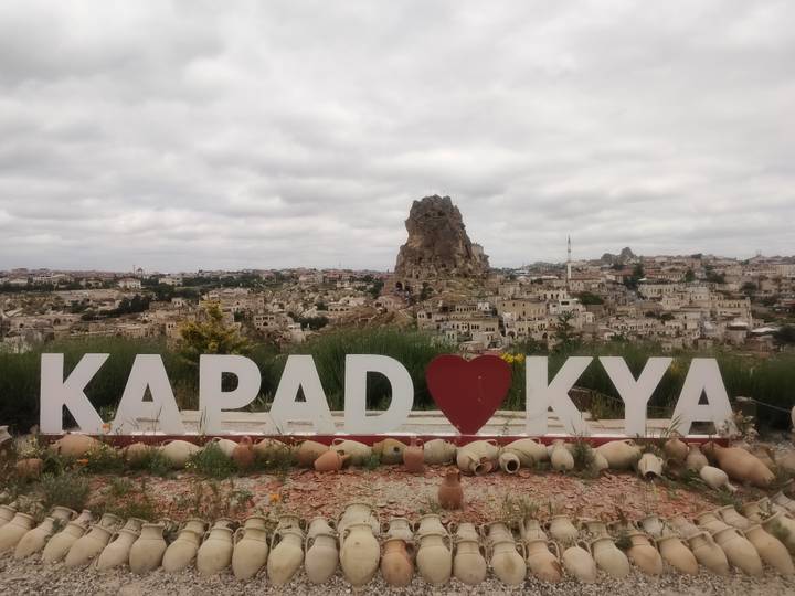 Scenic vista of Cappadocia town with large rock outcrop behind heart-shaped sign