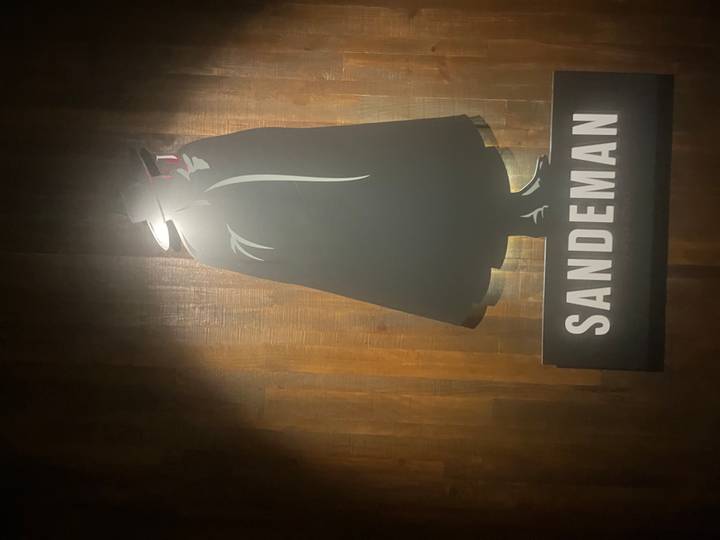 Back-lit wall sign of the Sandeman caped figure logo inside a dim tasting room