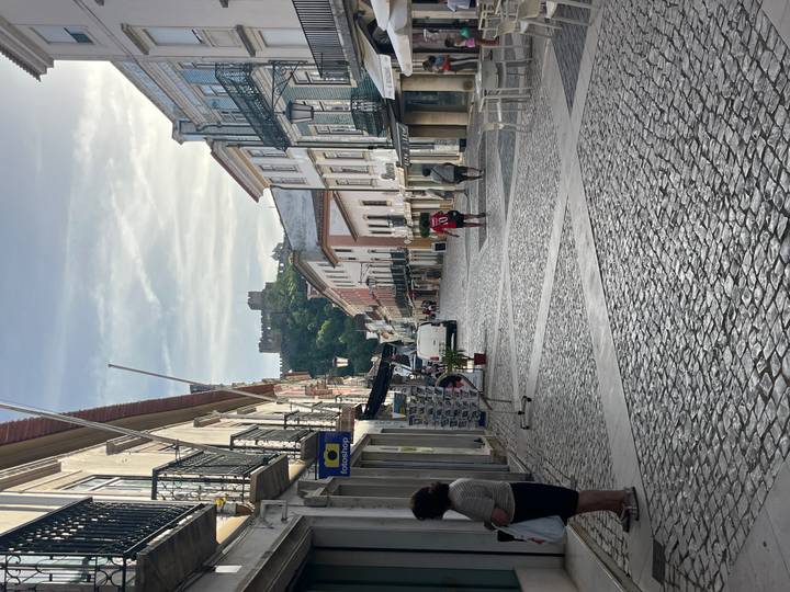 Wide cobbled street with distant hilltop castle, early morning light and locals walking
