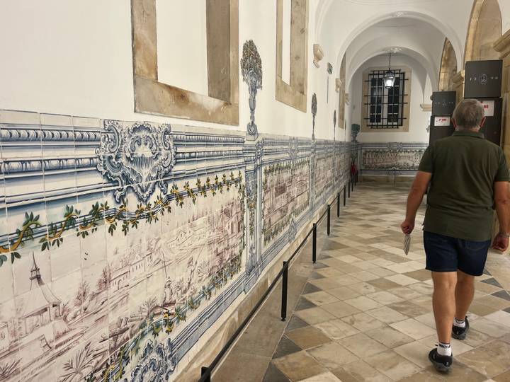 Long corridor lined with intricate blue-and-white azulejo panels inside a monastery