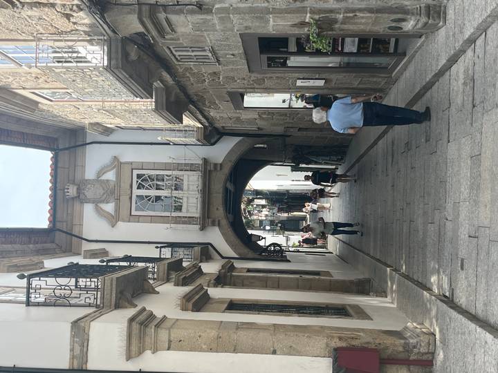 Stone archway street in an old town with heraldic crest above balcony