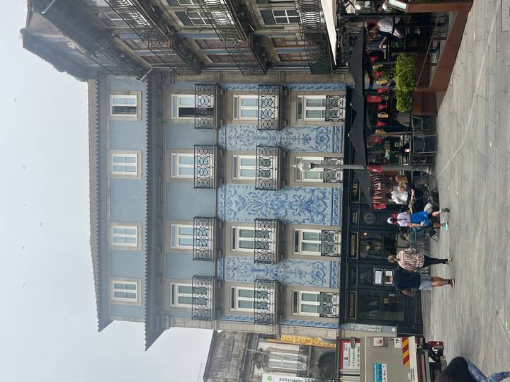 Blue azulejo-clad residential building overlooking a small square with families