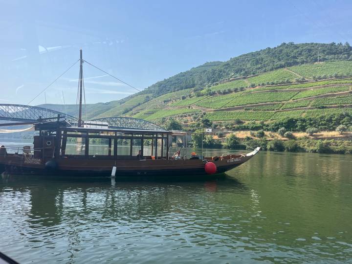 Traditional wooden river boat moored on the Douro with terraced vineyards on rolling hills