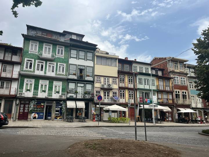 Row of colorful narrow townhouses with cafés in front of a cobblestone square