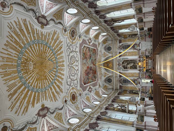 Ornate Baroque church interior with a gilded sunburst ceiling and richly decorated altar