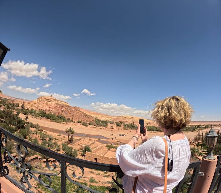 Traveler photographs the ancient hilltop ksar of Ait Benhaddou from balcony viewpoint.