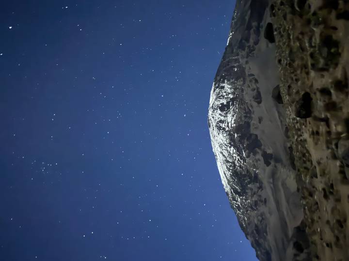 Snow-capped mountain summit beneath a clear star-filled night sky.
