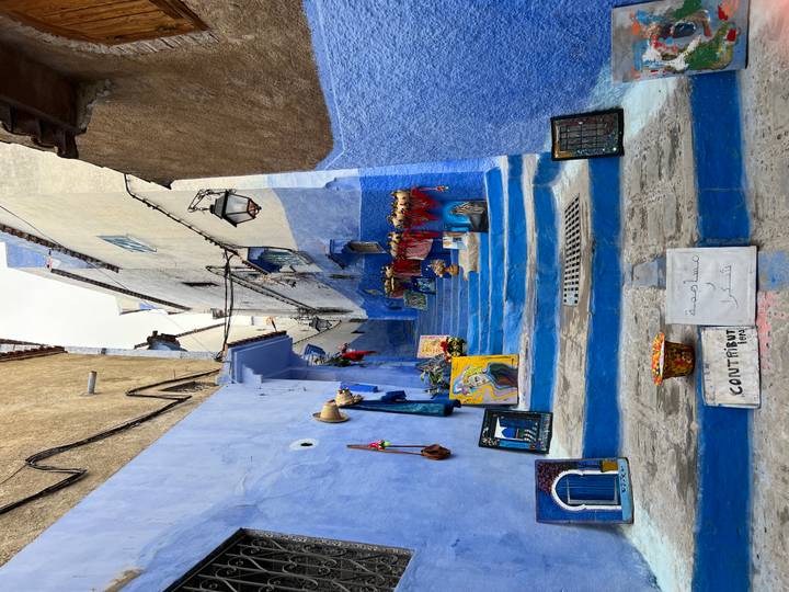 Narrow blue-painted stairway in Chefchaouen lined with local artwork and colorful crafts