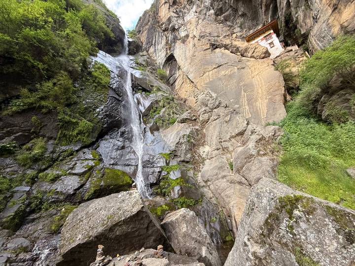 Steep rocky cliff with thin waterfall cascading beside bright green moss