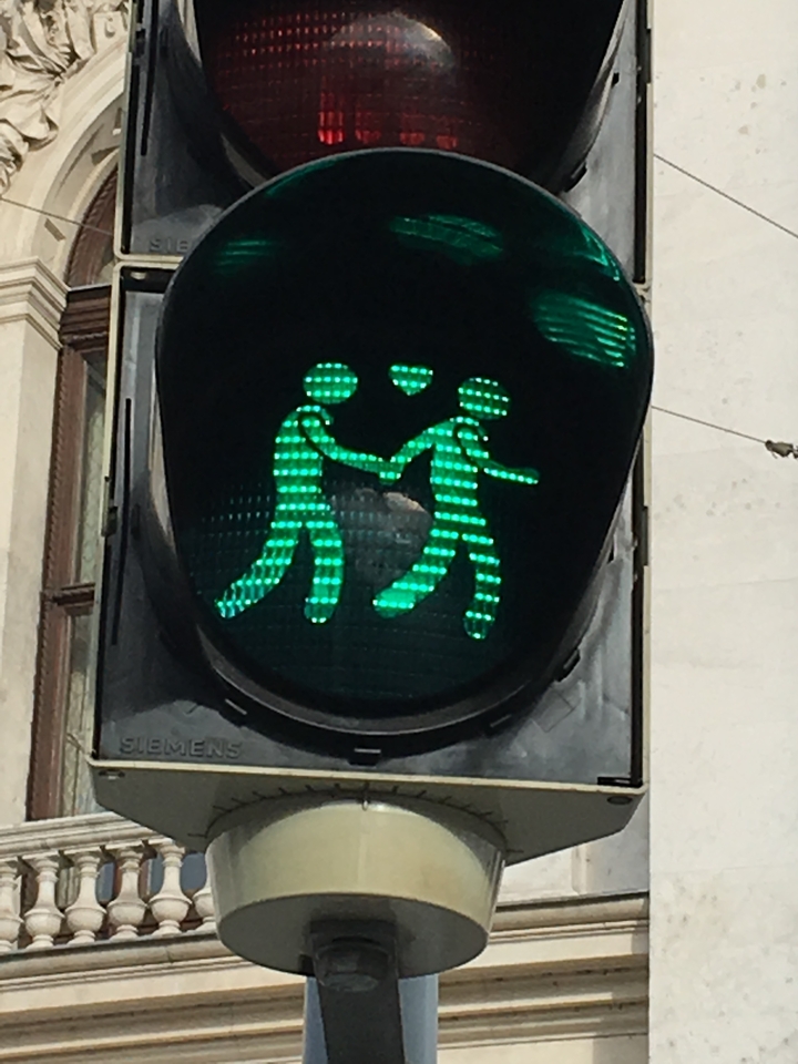 Unique pedestrian crossing signal with figures holding hands.