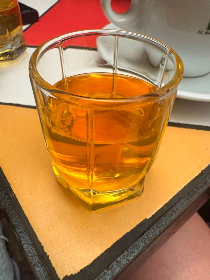 A small glass of golden Albanian raki sits on a table ready to be sampled.